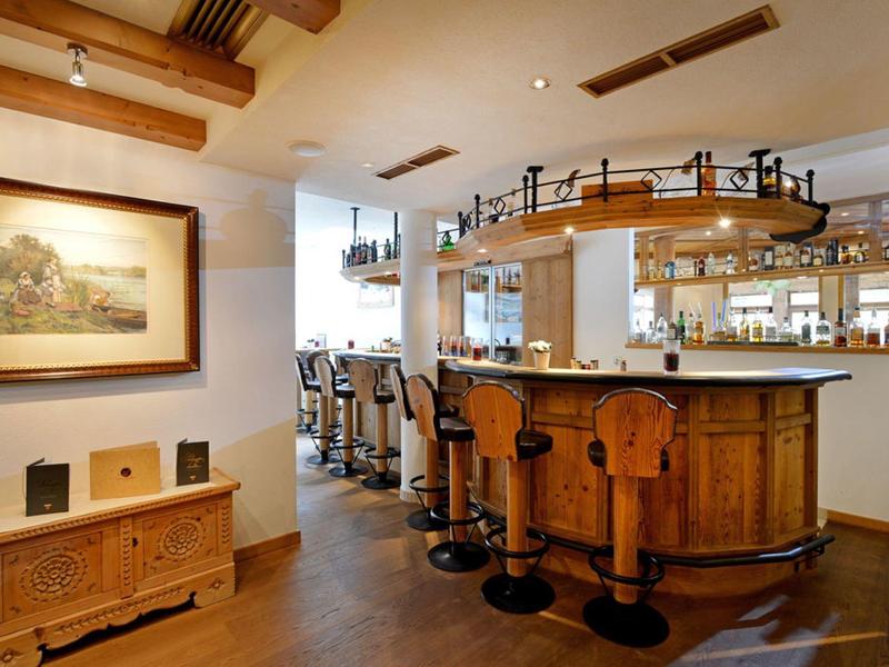 Gemütliche Bar mit Holztheke, vier Barhockern und warmem, einladendem Licht.