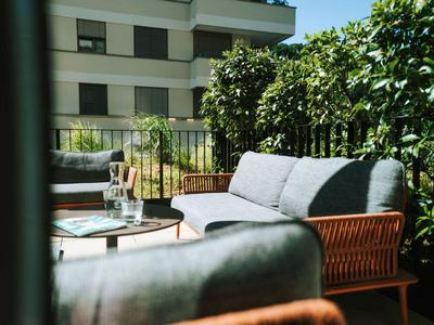 Gemütliche Terrasse mit modernen grauen Sofas und einem kleinen Tisch in einem Hotel.