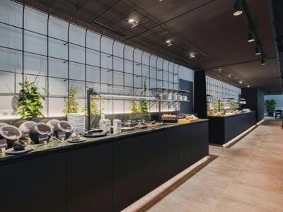 Moderner Frühstücksraum mit Buffet und Sitzbereich in hellem, offenem Raum.