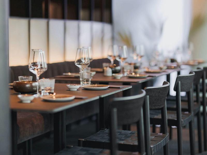 Elegantní jídelní stůl s pečlivě naaranžovaným příborem a sklenicemi ve stylové restauraci.