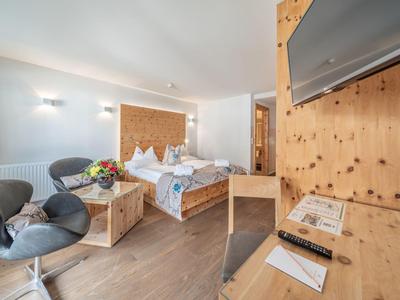 Helles Hotelzimmer mit gemütlichem Bett, Sesseln und Holzmöbeln.