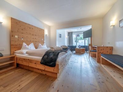 Helles Hotelzimmer mit Holzfußboden, großem Bett, moderner Einrichtung und Zugang zum Balkon.