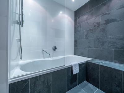 Modernes Badezimmer mit Badewanne und verfliesster Wand in neutralen Farben.