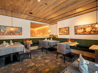 Modern eingerichteter Hotelrestaurant-Innenraum mit Holztäfelung und gedeckten Tischen.