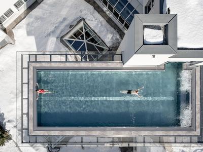 Überblick auf einen rechteckigen Pool mit zwei Schwimmern und moderner Architektur.