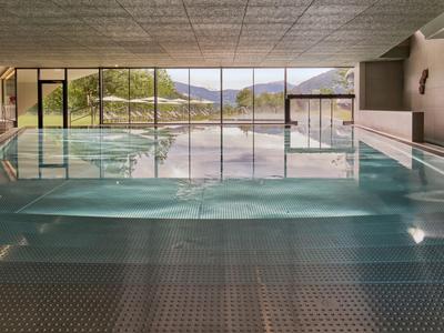 Moderner Innenpool mit großen Glasfenstern und Blick auf Berge und Natur.