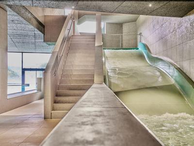 Hell beleuchteter Poolbereich mit Wasserrutsche und Treppe in einem Hotel.