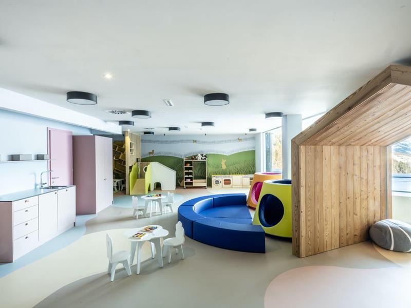 Area giochi per bambini in una stanza luminosa e moderna con sedute colorate e tavoli