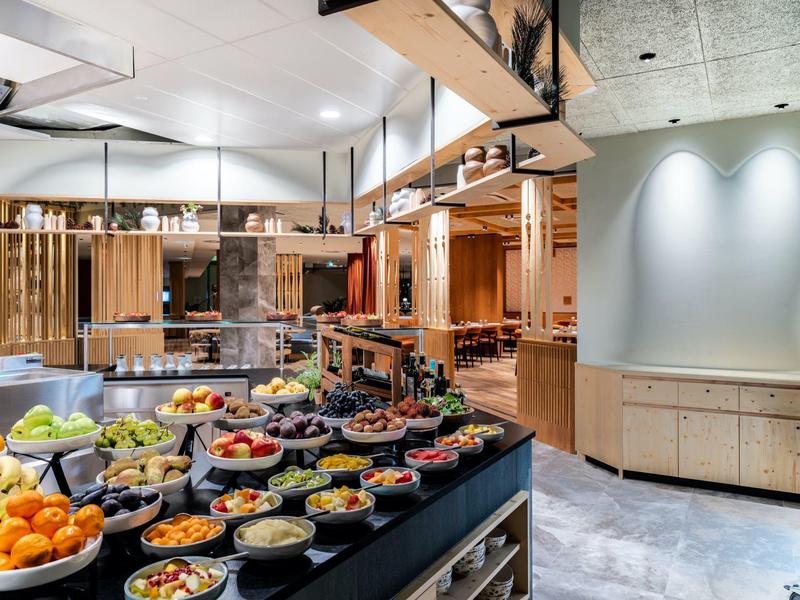 Area buffet con frutta fresca e snack in un interno di ristorante moderno.