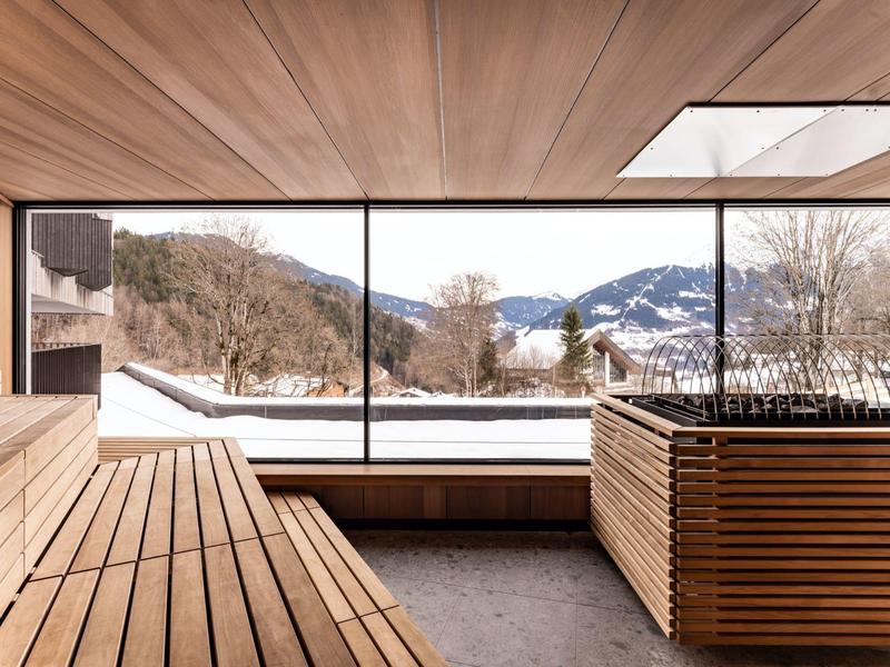 Spazio moderno con ampie finestre panoramiche che mostrano montagne innevate e alberi.