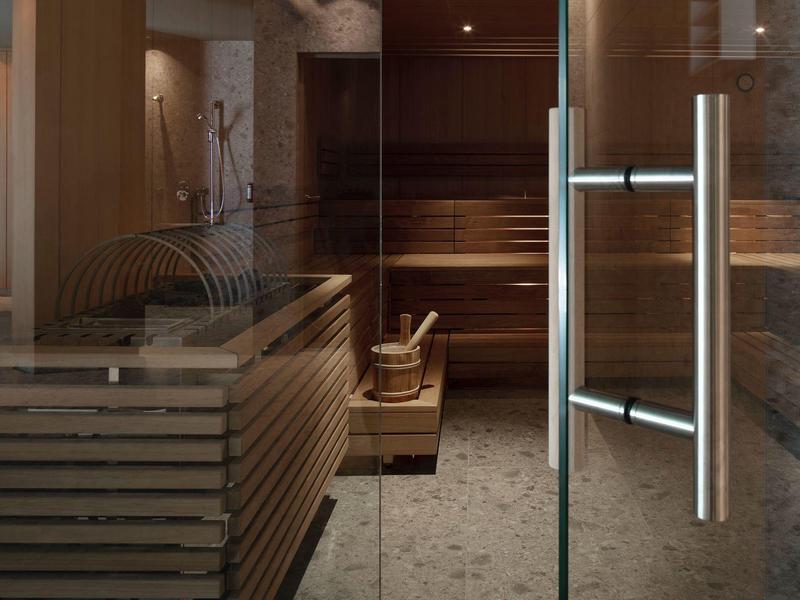 Sauna in legno con porte moderne in vetro e metallo all'interno di una spa.