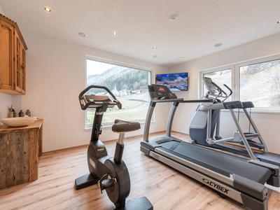 Palestra luminosa con attrezzature moderne e grandi finestre con vista sulle montagne.