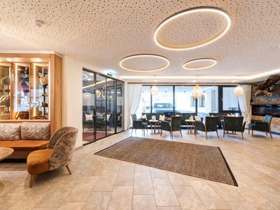 Heller, moderner Raum mit großen Fenstern, runden Deckenleuchten und gemischter Sitzgruppe.