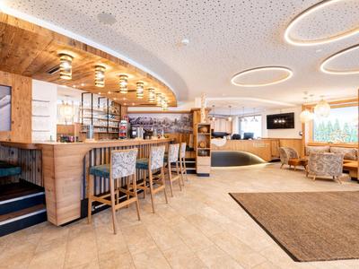 Bar dell'hotel luminosa e moderna con dettagli in legno e aree salotto accoglienti.