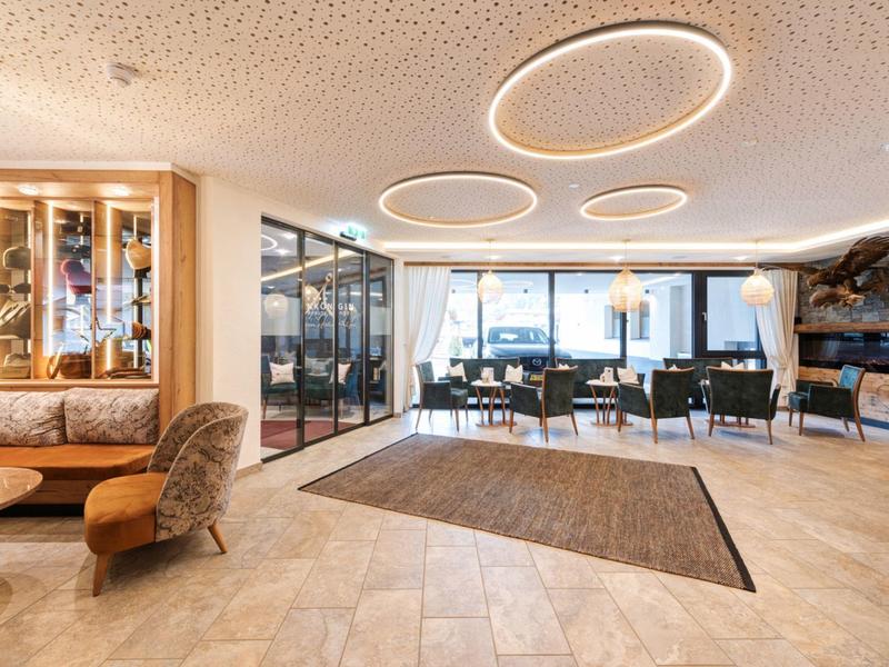 Heller, moderner Raum mit großen Fenstern, runden Deckenleuchten und gemischter Sitzgruppe.