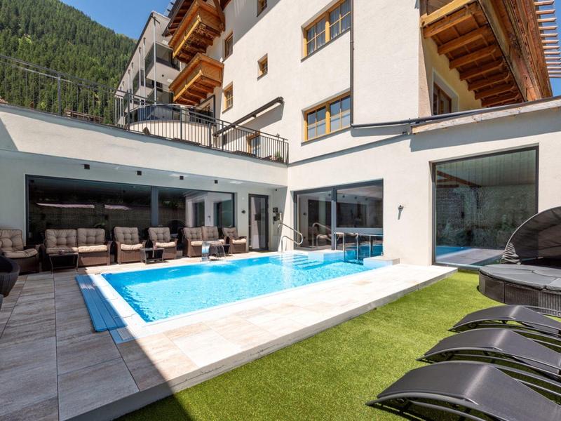 Moderner Außenbereich mit klarem rechteckigem Pool, Grautönen, Holz und grüner künstlicher Wiese.