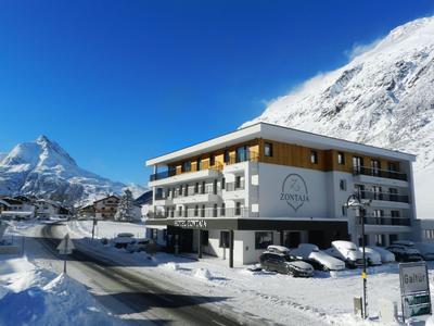 Edificio moderno di un hotel in un paesaggio montano innevato sotto un cielo limpido.