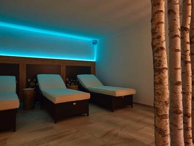 Ruheraum mit drei gepolsterten Liegen aus Holz und gedämpftem blauen LED-Licht an der Wand.