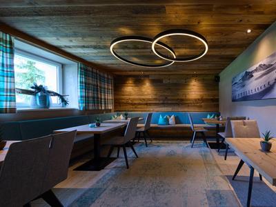 Sala da pranzo moderna con soffitto in legno, grandi finestre e luci circolari a soffitto.