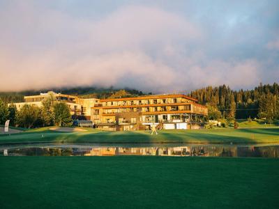 Grande hotel circondato da campi verdi e alberi sotto un cielo nuvoloso.