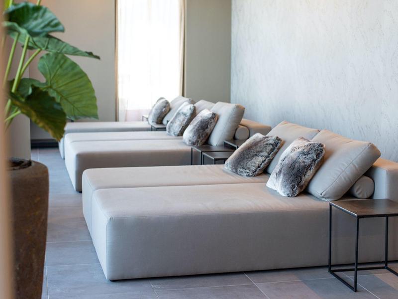 Poltrone moderne con cuscini vicino a una grande finestra e pianta verde nella hall dell'hotel