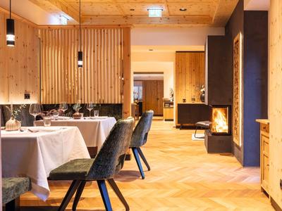 Restaurante luminoso con paredes de madera, chimenea y mesas decoradas con manteles blancos.