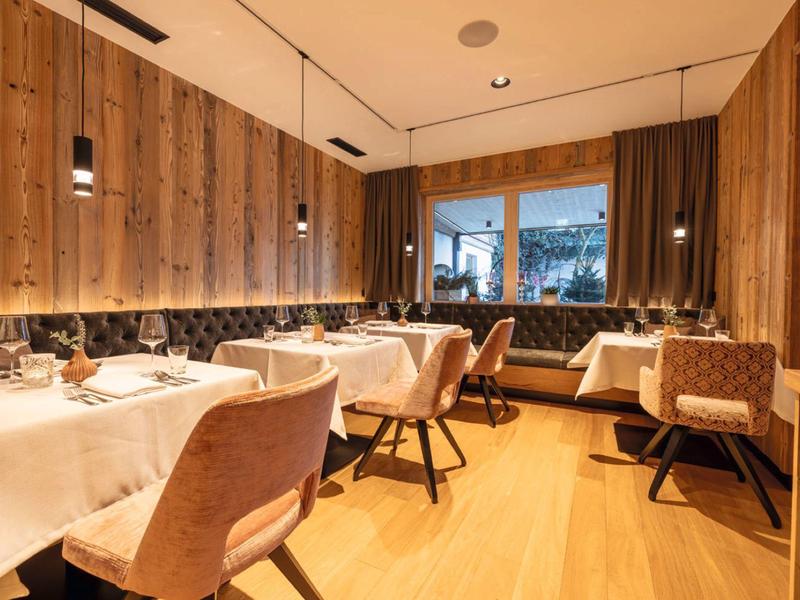 Elegant restaurant with wooden walls, tablecloths, and city view at dusk.