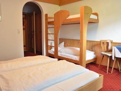 Ein einfach eingerichtetes Zimmer mit Etagenbett, Doppelbett und Holzmöbeln.