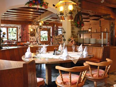 Gemütlicher Holzesstisch mit eingedeckten Plätzen in einem rustikalen Restaurant mit Fensterblick.