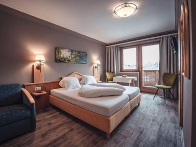 Acogedora habitación de hotel con cama doble, balcón, zona de estar y diseño moderno.