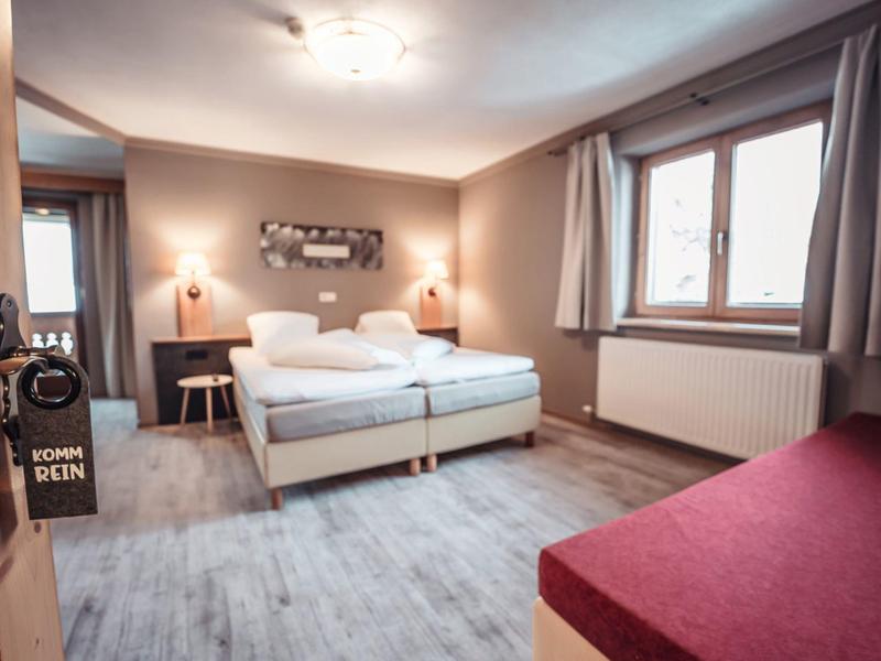 Lichte hotelkamer met tweepersoonsbed, nachtkastjes en raam met gordijnen.