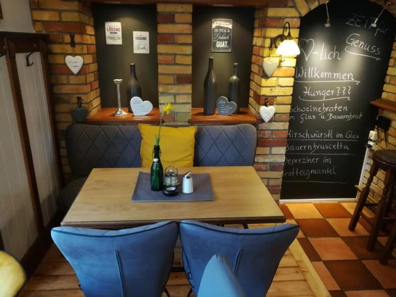 Gezellige hoek met houten stoelen, kussens en krijtbordwand in een restaurant.