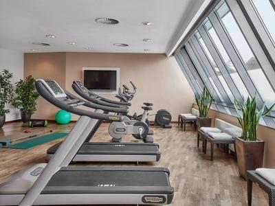 Palestra moderna con tapis roulant, area salotto e grandi finestre.