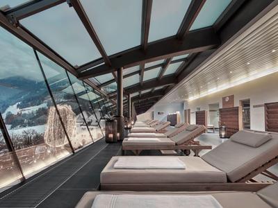 Moderní lounge s lehátky a panoramatickými okny s výhledem na zasněžené hory.