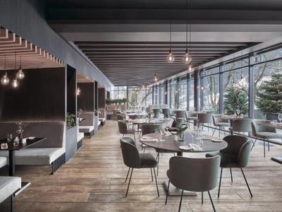 Nowoczesna, jasna restauracja z dużymi oknami i stylowymi miejscami do siedzenia.