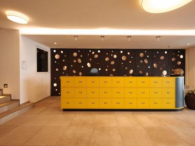 Area reception moderna con bancone giallo e parete decorativa in hotel.