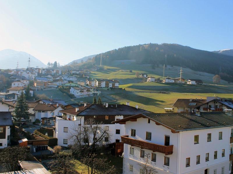 Vue d'un village avec des maisons blanches et des montagnes en arrière-plan en plein jour.