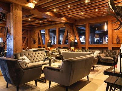 Coin salon d'hôtel confortable avec fauteuils et accents en bois sous un éclairage chaleureux.