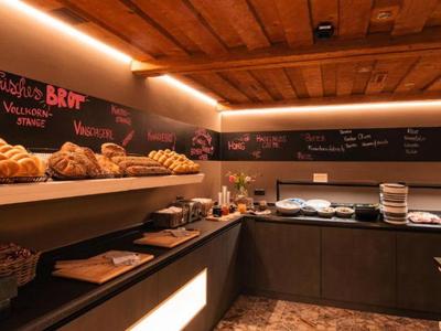 Cuisine d'hôtel confortable avec plafond en bois, plans de travail sombres et pain frais.