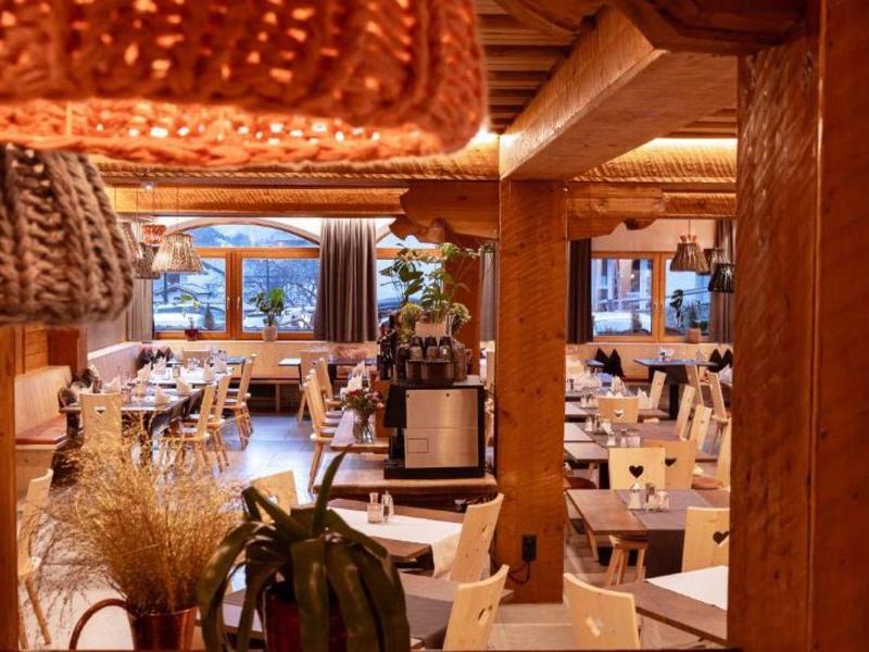 Gemütliches Restaurant mit hölzernen Möbeln, warmem Licht und dekorativen Lampen im Alpenstil.