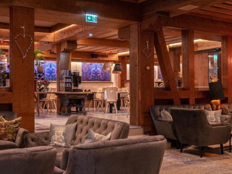 Gemütliches Restaurant mit Holzbalken, Polstersesseln und warmem Licht für entspanntes Essen.