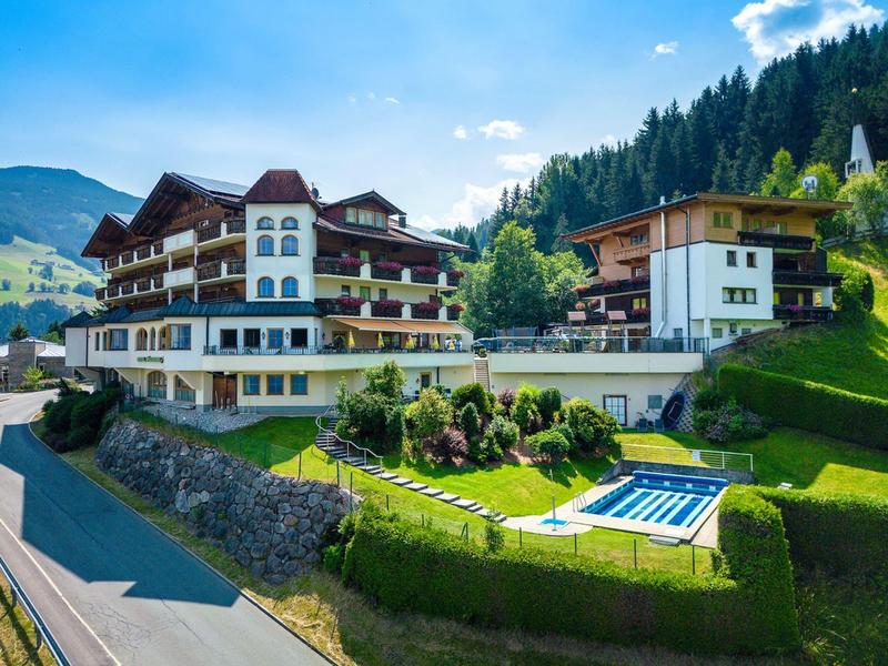 Velká hotelová budova v horách s upravenou zahradou a čistým venkovním bazénem