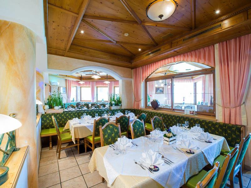 Útulná restaurace s ozdobným dřevěným nábytkem a prostřenými stoly pod dřevěným stropem.