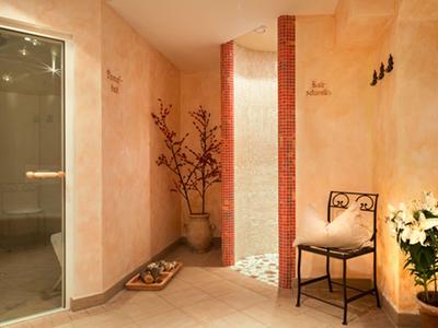 Teplá wellness místnost se židlí, rostlinami a jemným osvětlením pro relaxaci.