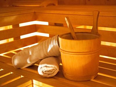 Dřevěné vědro s naběračkou a ručníky v dřevěné sauně.