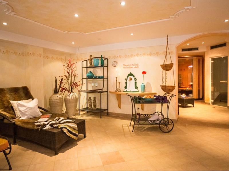 Pohodlná místnost s koženým lehátkem, dekorativními rostlinami a teplým osvětlením v pozadí.