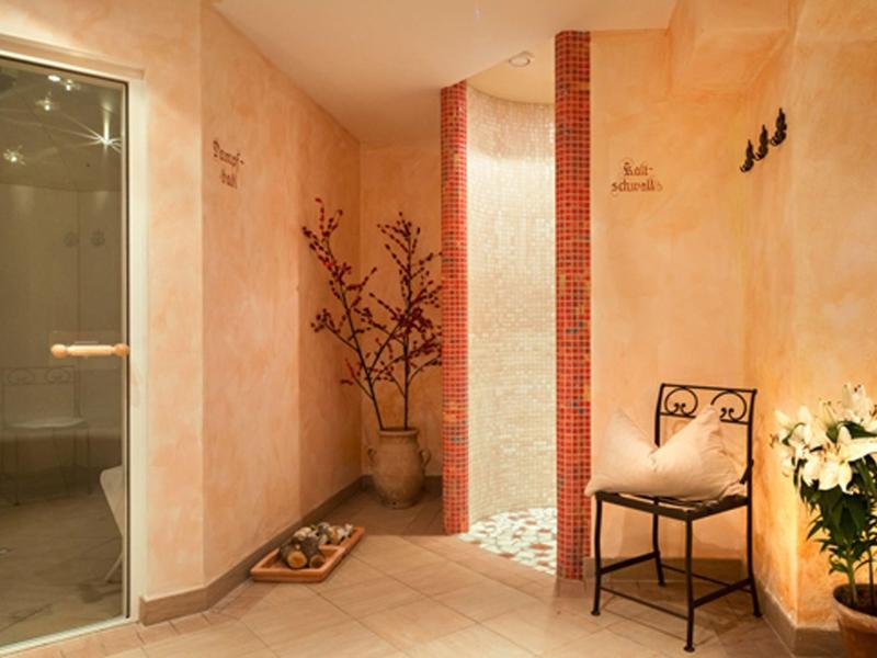 Teplá wellness místnost se židlí, rostlinami a jemným osvětlením pro relaxaci.