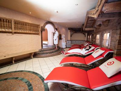 Area relax con lettini rossi, coperte di pelliccia e accappatoi in una lounge spa riscaldata.