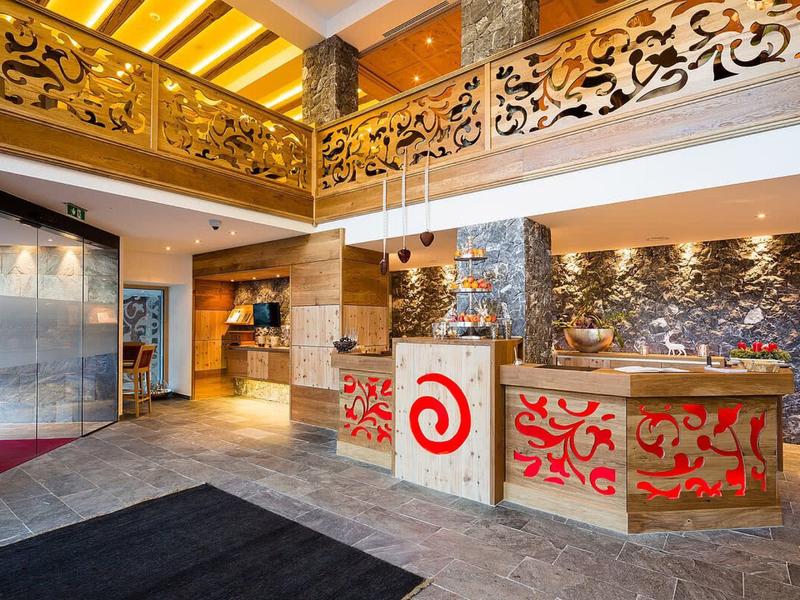 Luminoso ingresso di hotel con reception moderna e balcone decorato in oro.