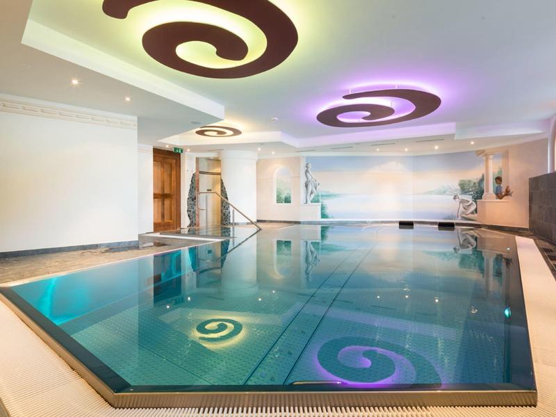 Piscina interna moderna con illuminazione indiretta e luci decorative a soffitto in un hotel.